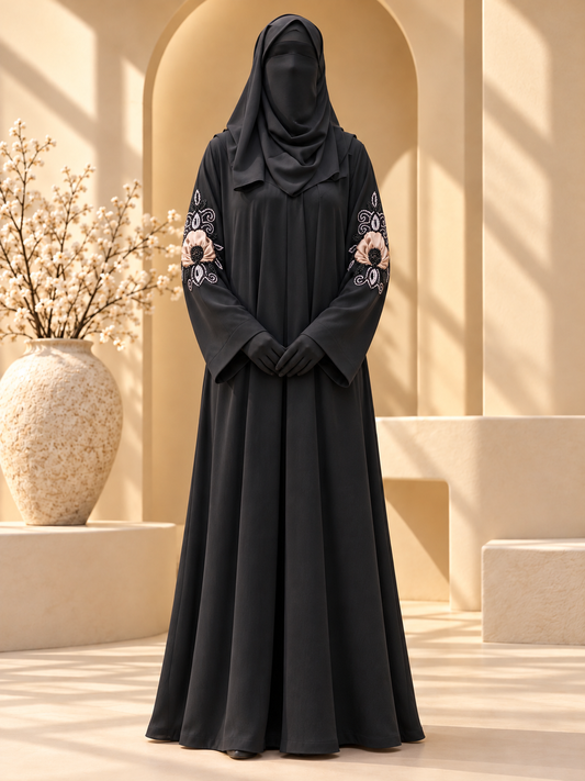 Black Gul-e-Rang abaya with peach fabric floral applique and sleeve beadwork in sunlit courtyard